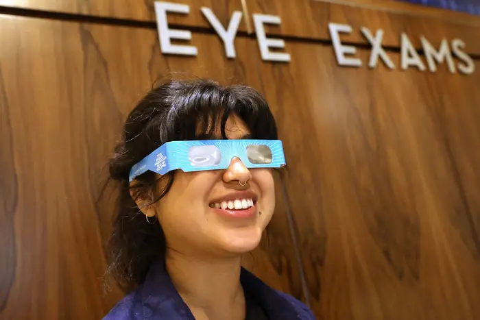 An employee at Warby Parker tries on viewing glasses in NYC<br>